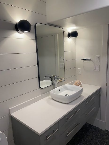 A bathroom with a sink, mirror and lights.