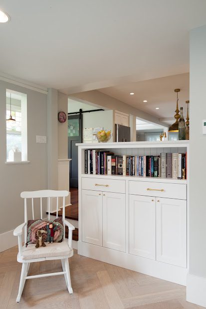 A white chair and bookcase in the corner of a room.