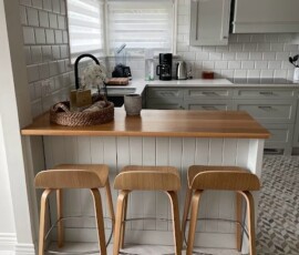 Charming kitchen with a wooden breakfast bar, modern gray cabinetry, and geometric tile flooring, showcasing a blend of contemporary and cozy design by Campo Design in Victoria, BC.