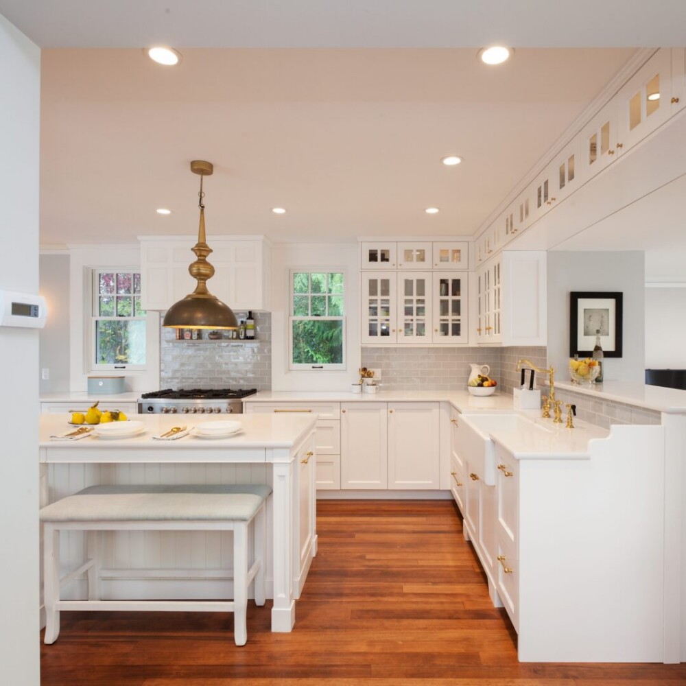 A kitchen with white cabinets and wooden floors
