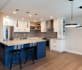 Spacious and modern kitchen featuring a bold blue island, sleek white cabinetry, and contemporary pendant lighting, designed by Campo Design for stylish functionality in Victoria, BC.