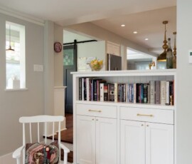 A white chair and bookcase in the corner of a room.